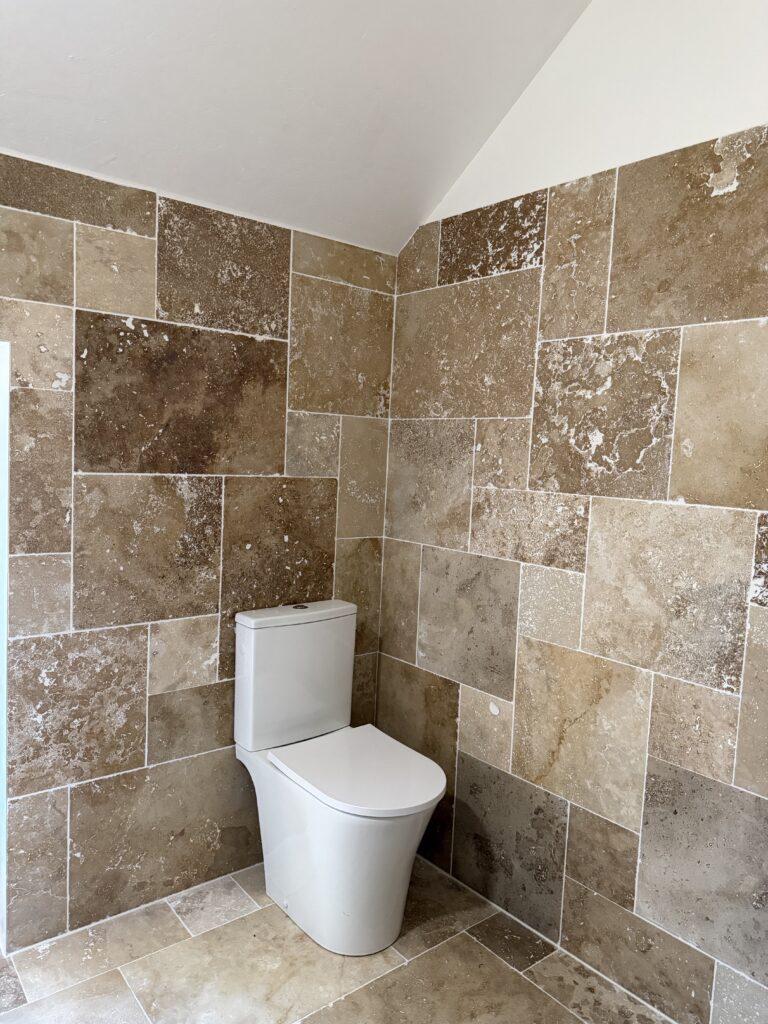 Salle de bain rénovée à Malesherbes : WC suspendu et murs en pierre naturelle
