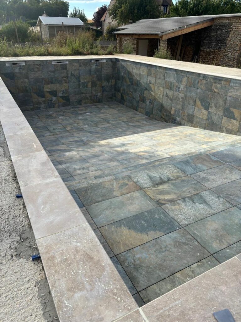 Piscine en pierre de Bali terminée avec margelles en travertin et joints époxy à Malesherbes